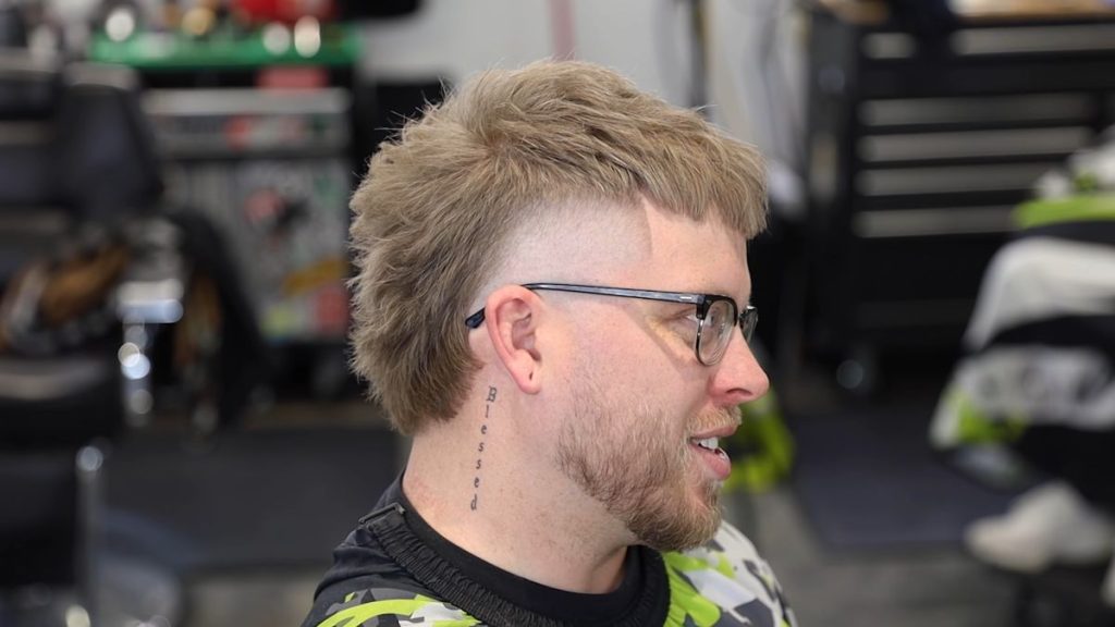 Stylish high taper mullet hairstyle with a textured top and a high, skin fade.