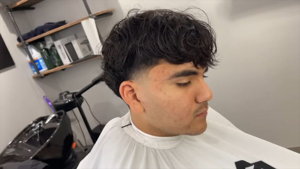 Man with a long taper fade haircut and textured style on top