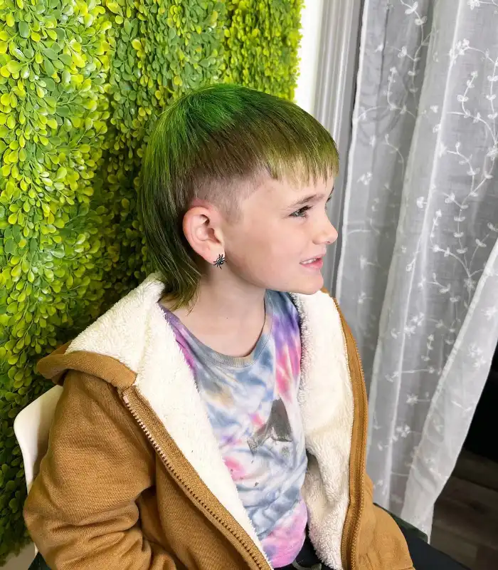A young boy with a mullet hairstyle, featuring vibrant green highlights