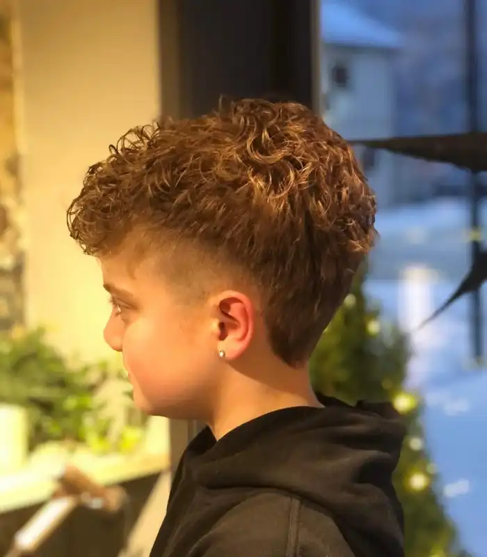 A young boy with a messy mullet hairstyle. A young boy with a deliberately messy mullet, featuring tousled layers and a textured finish.