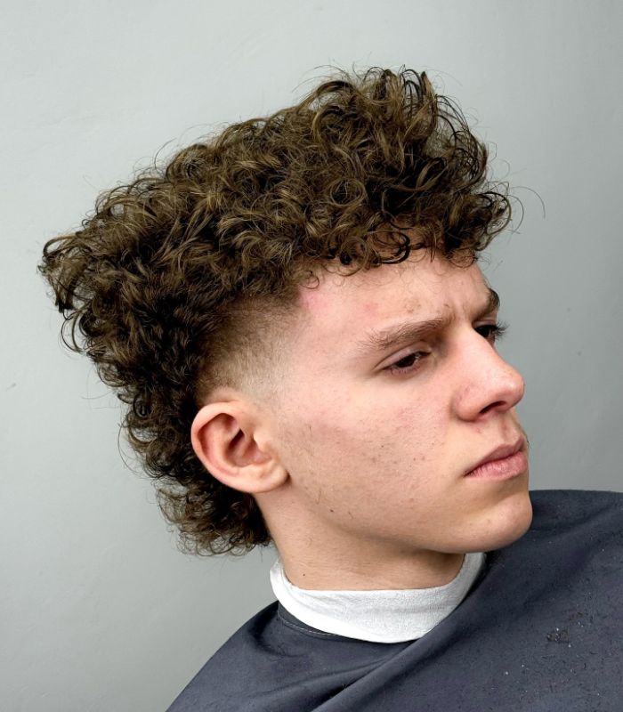 A young boy with a trendy undercut mullet, featuring shaved sides and a long, textured mullet at the back.