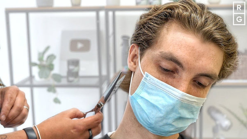 Barber styling an Ivy League haircut showing short sides and textured top swept back with volume