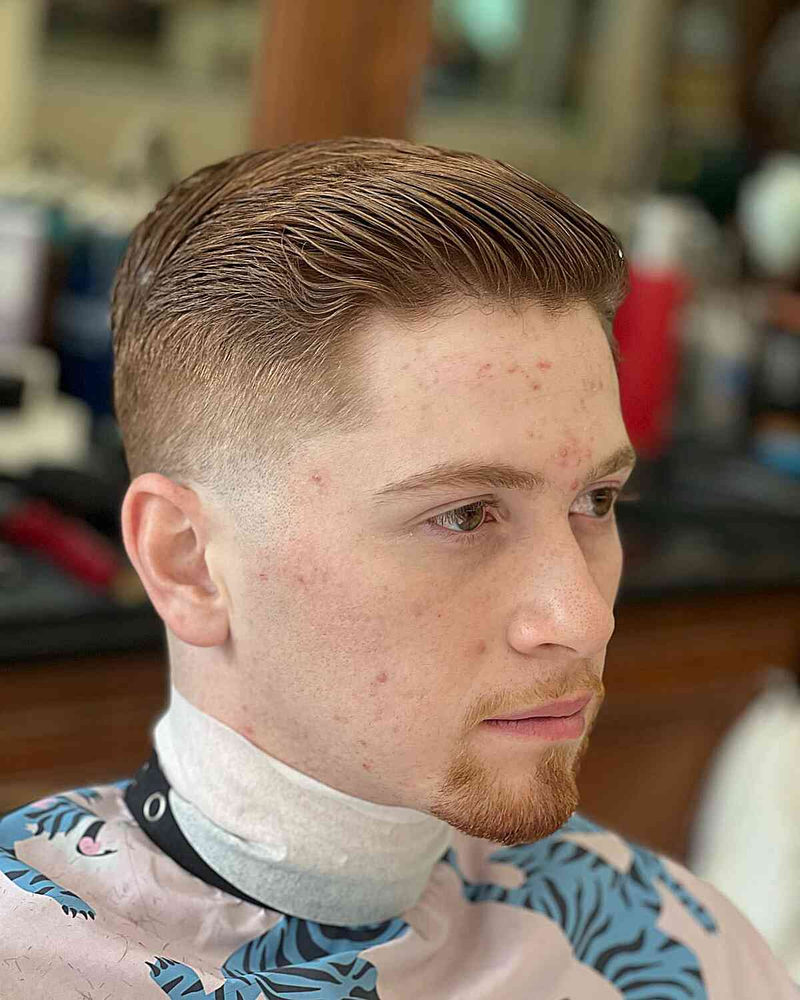 Classic Ivy League haircut with smooth top styled backward and tight fade on sides and back
