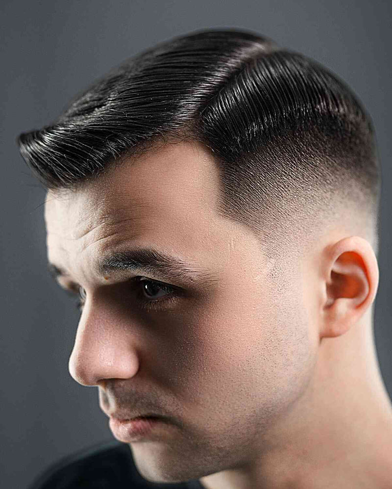 Ivy League haircut with side part featuring medium length top styled back with gradual fade on sides
