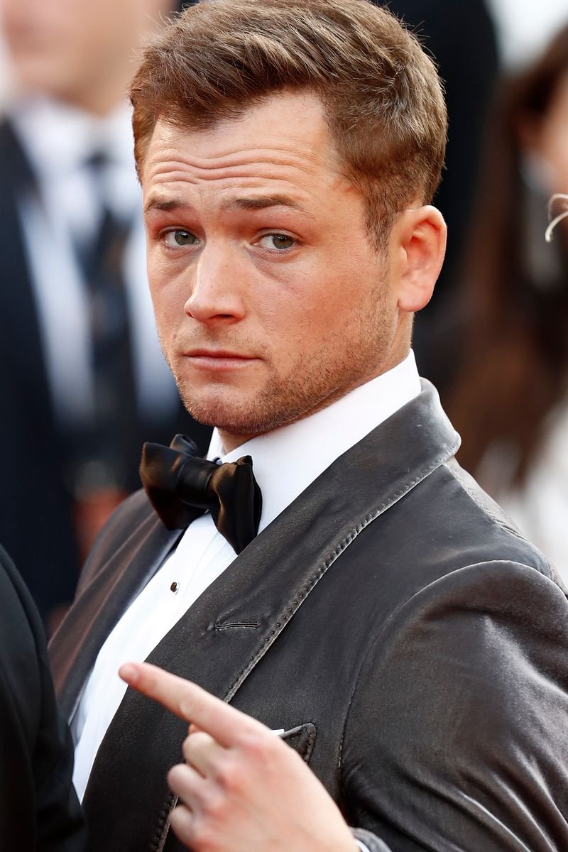 Taron Egerton at event with swept back hairstyle showing his natural widow's peak