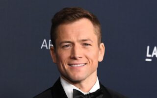 Taron Egerton medium length hairstyle with widow's peak swept back