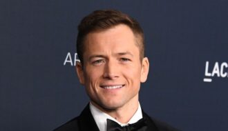 Taron Egerton medium length hairstyle with widow's peak swept back