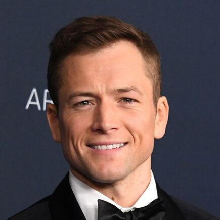 Taron Egerton medium length hairstyle with widow's peak swept back