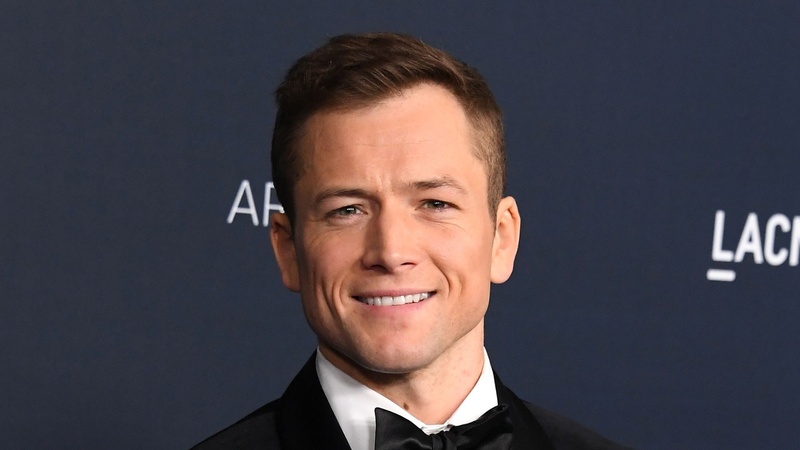 Taron Egerton medium length hairstyle with widow's peak swept back