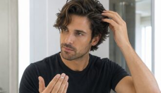 A fictional male model gently loosening dry waves with his fingertips while using a small amount of grooming cream.